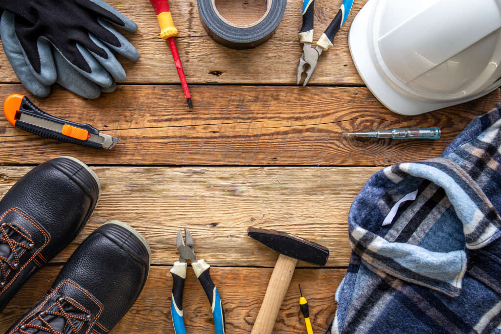 Set of repair tools and work uniform on wooden background, flat lay.